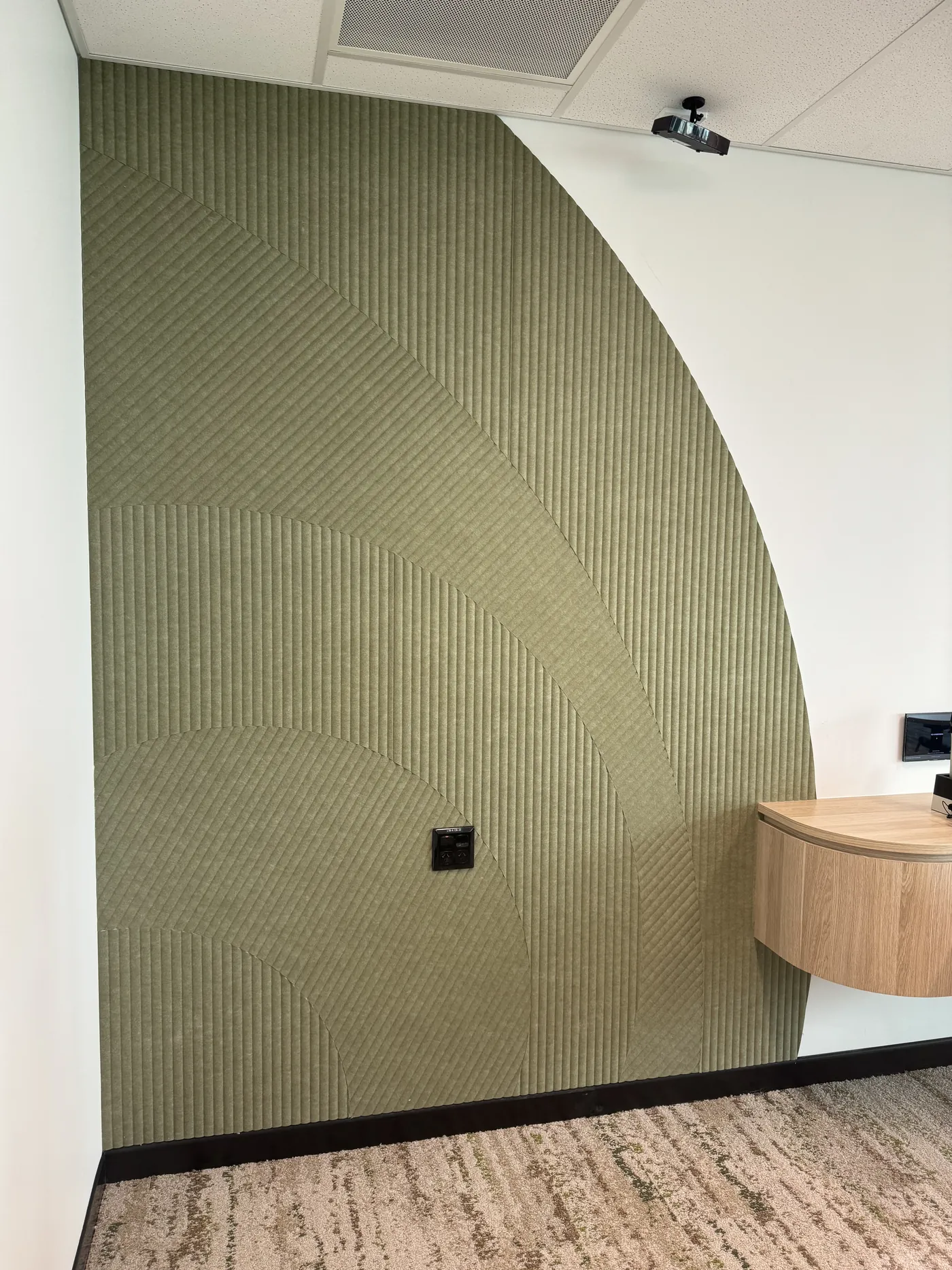 Close detail of olive green ribbed acoustic panel with curved edge