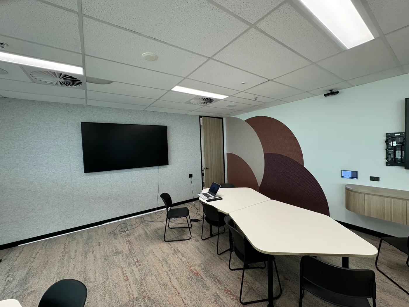 Meeting room with circular acoustic feature wall and grey acoustic panels behind a display