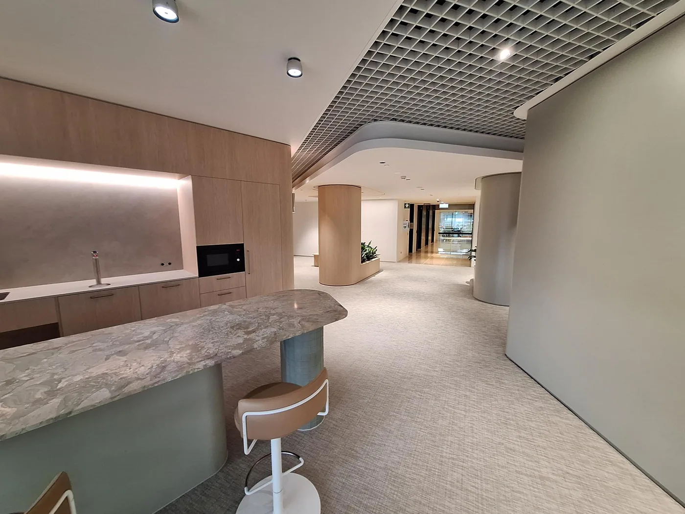 Curved ceiling bulkhead meeting recessed open-grid acoustic ceiling in a finished workplace