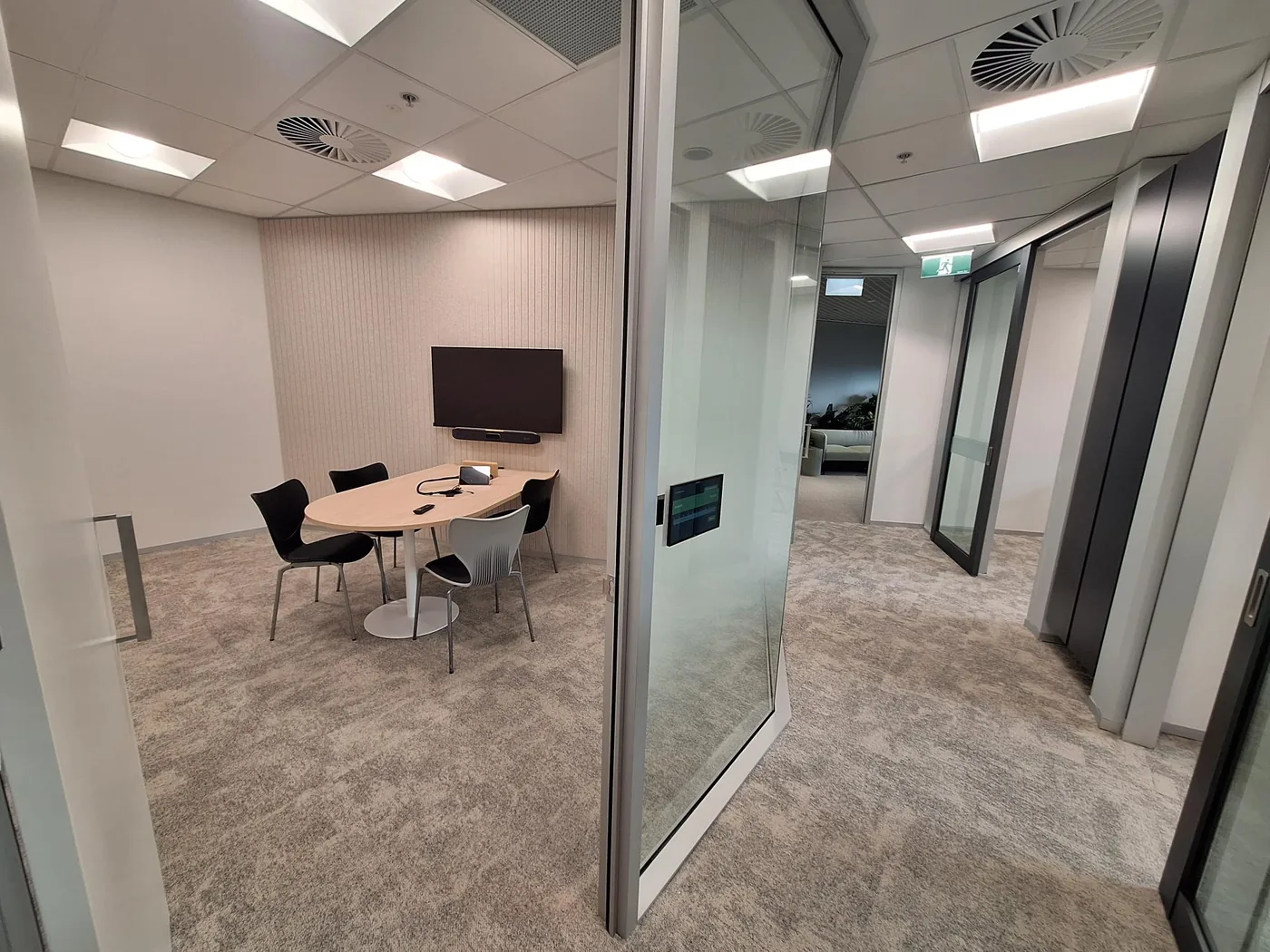Glass meeting room with acoustic tile ceiling and timber-slat feature wall