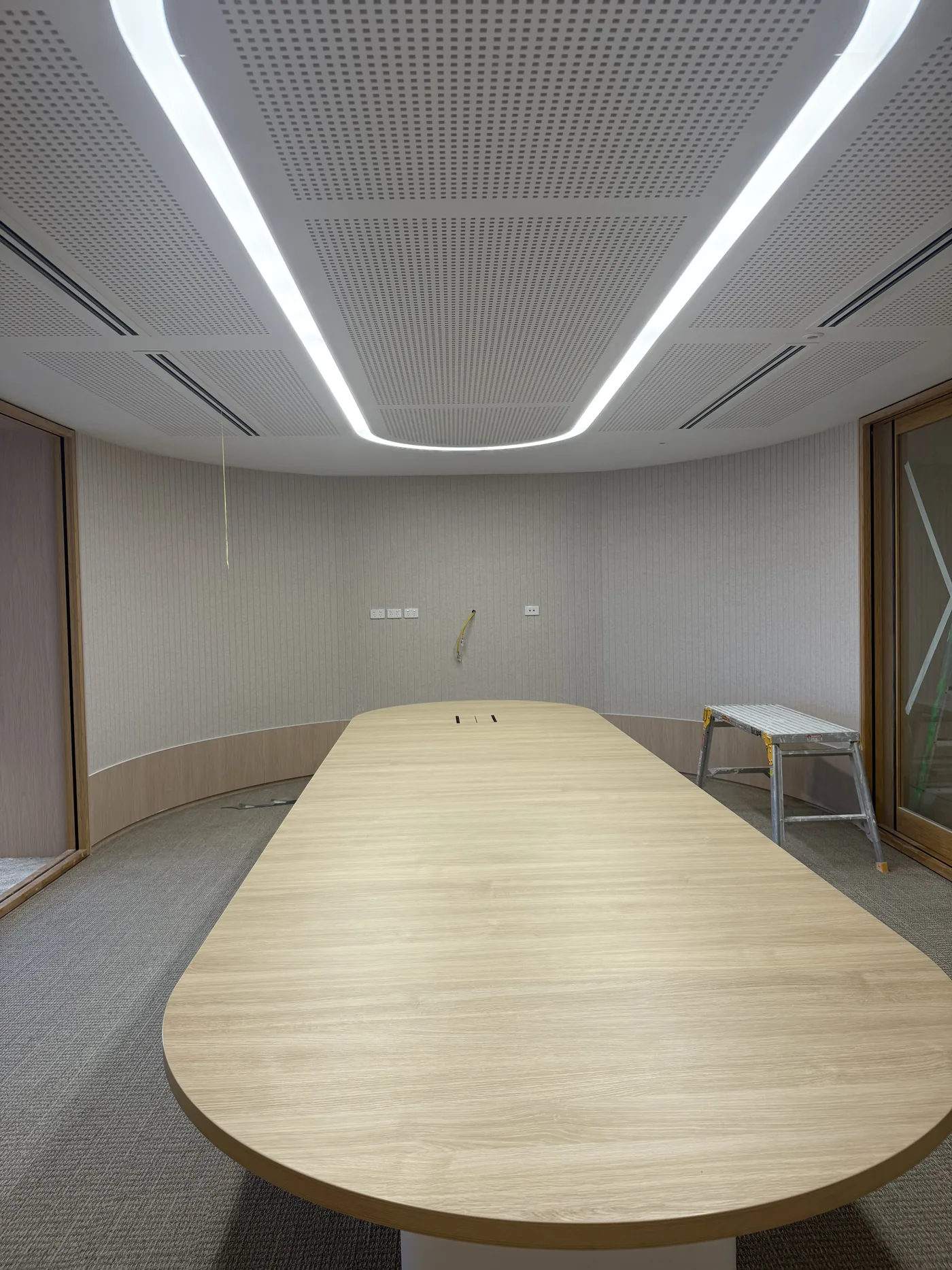 Ceiling acoustics install in a curved boardroom — perforated tiles and integrated lighting