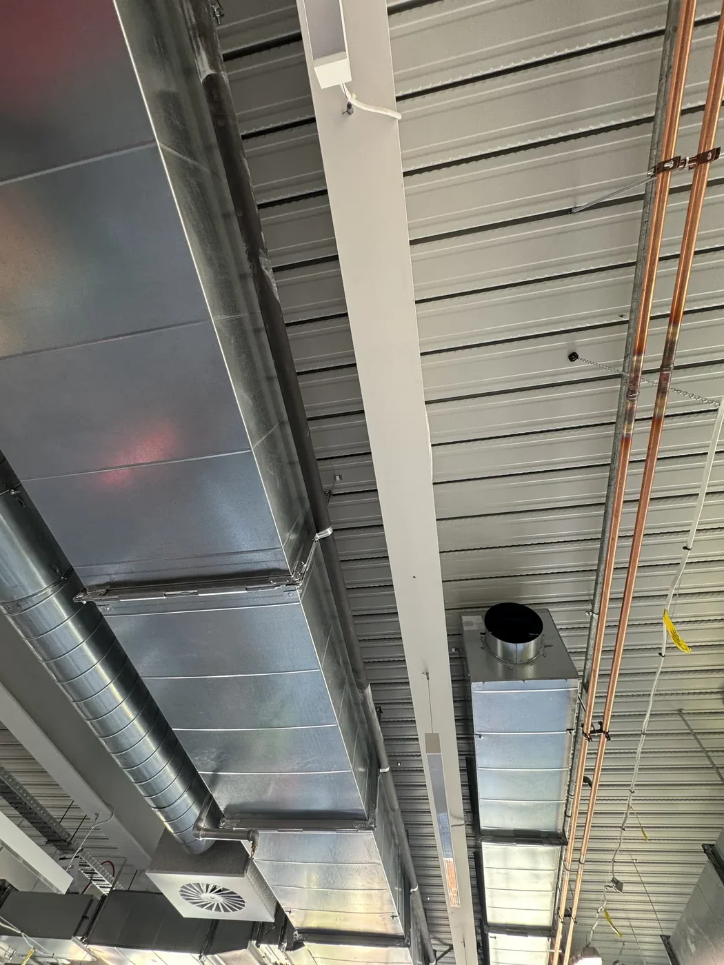 Close detail of galvanised ducts, copper pipes and cable tray before panels