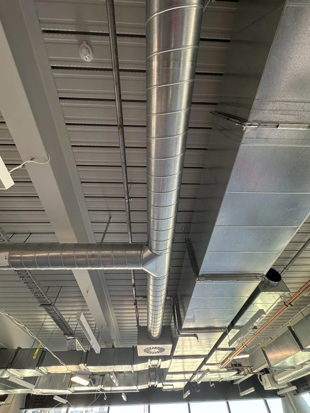 Looking up at spiral and rectangular ducts on corrugated deck before acoustic install