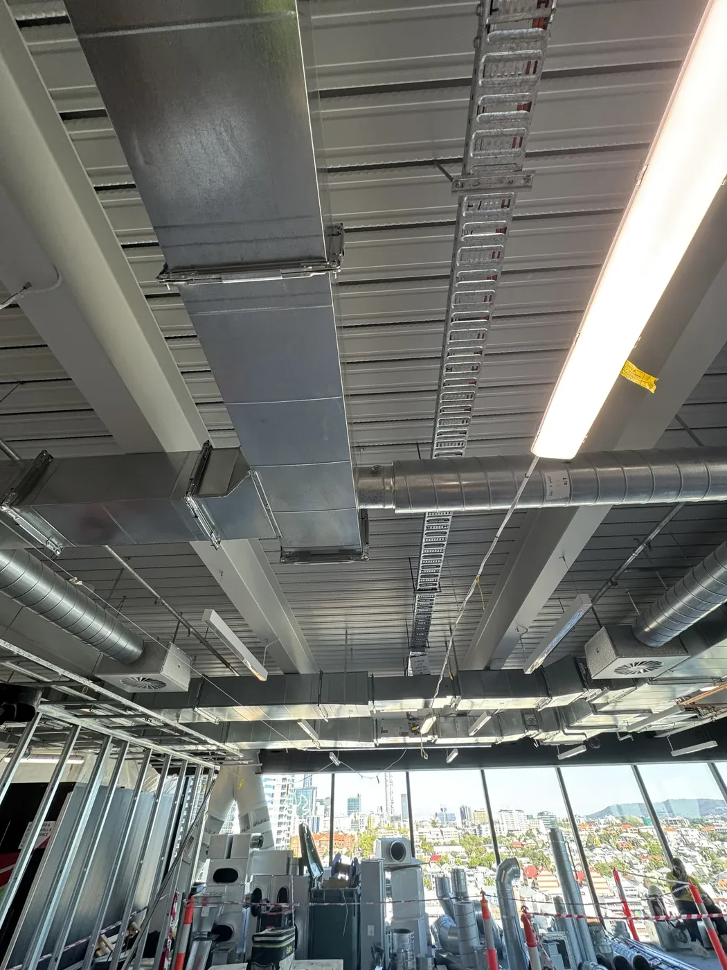 Open-plan floor with exposed ceiling services and city skyline through glass