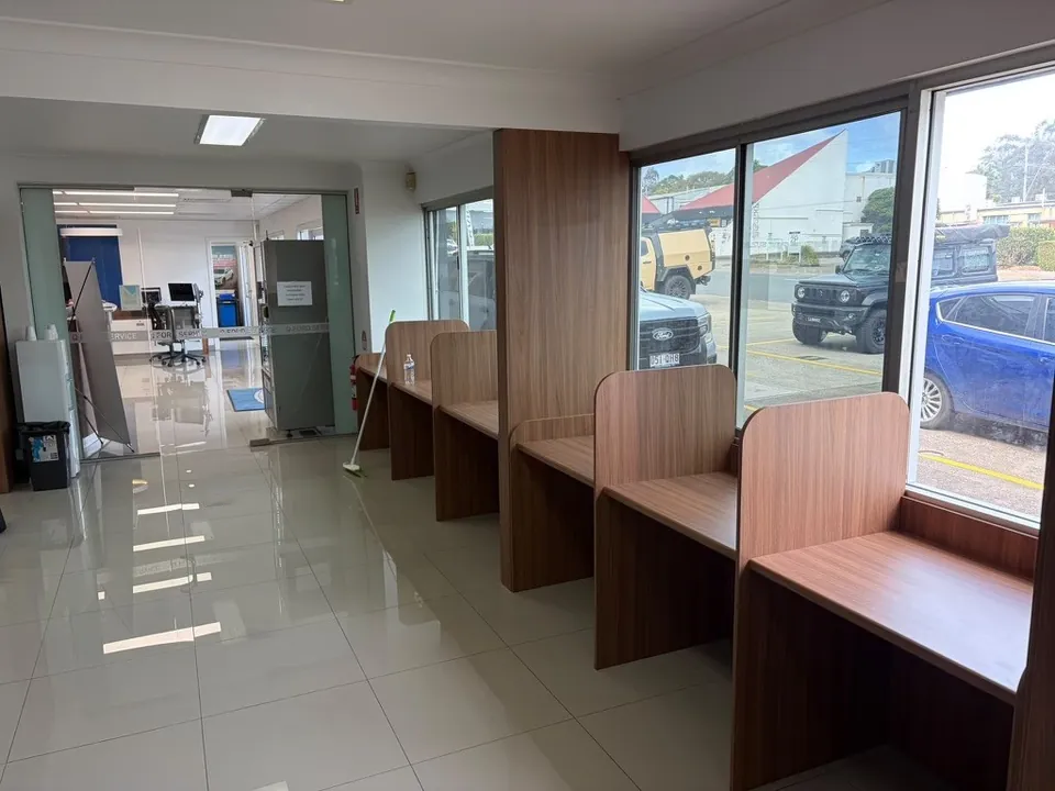 Row of custom walnut study booths along the showroom windows of a Springwood car dealership, joinery by HPCI