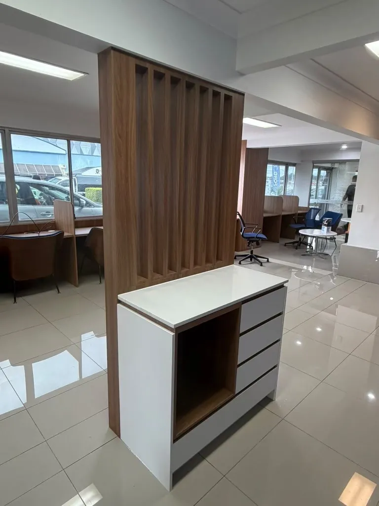 Custom walnut slatted timber screen with white drawer unit and stone benchtop in a car dealership showroom
